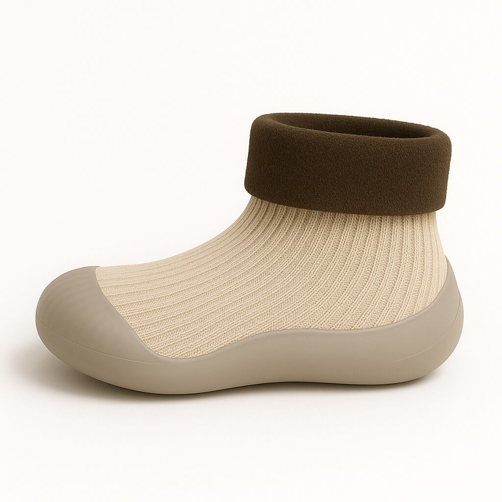 Zijaanzicht van een beige sokschoentje met ribgebreide stof, zachte pasvorm en veilige antislip zool voor peuters en kleuters