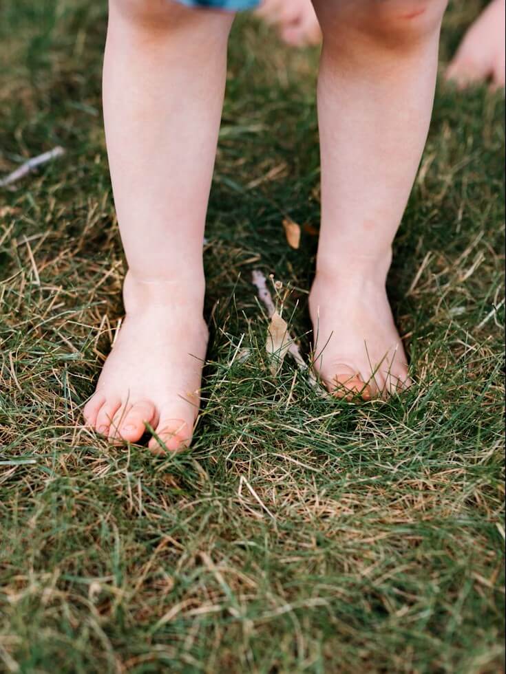Blote kindervoetjes op gras – symboliseert barefoot-beweging en natuurlijke ontwikkeling