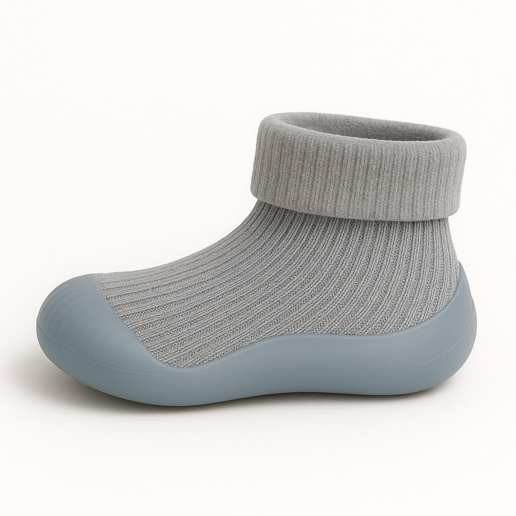 Zijaanzicht van een grijs sokschoentje met ribstof en stevige anti-slip zool – lichtgewicht en flexibel voor kleine kindervoetjes