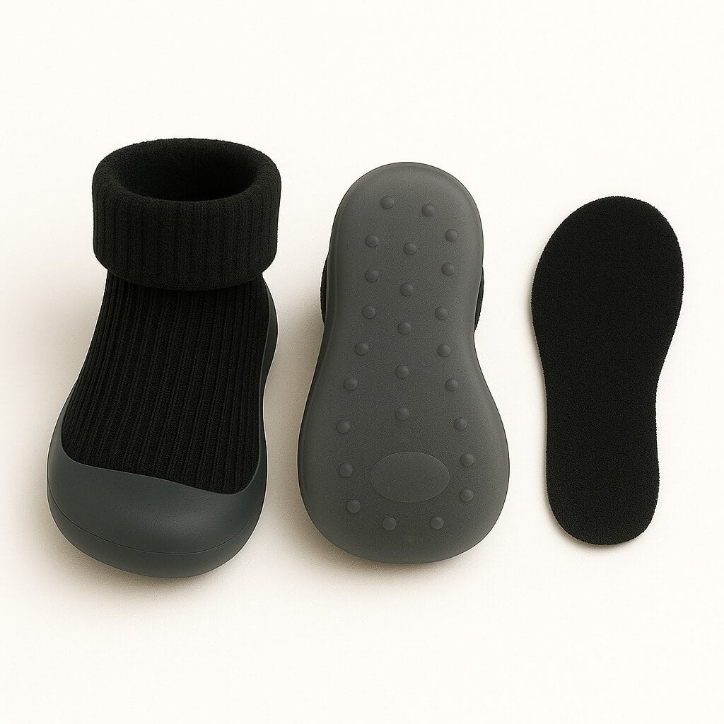 Onderzijde van zwarte kindersloffen met transparante antislip zool en zachte uitneembare inlegzool – praktisch en veilig voor peuters
